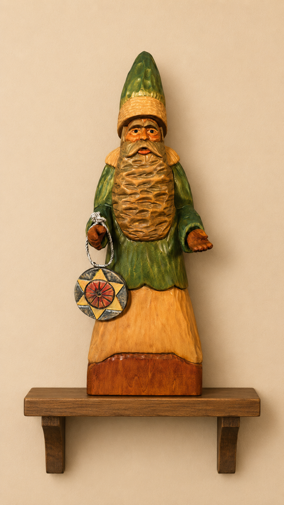 Father Christmas wood carving in green robe holding a star medallion, displayed on a wooden shelf