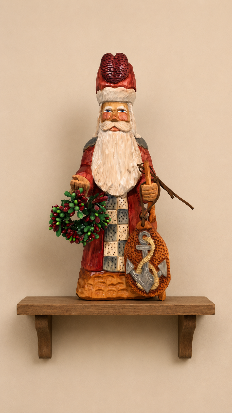 Father Christmas wood carving in red robe holding a holly wreath and anchor sack, displayed on a wooden shelf