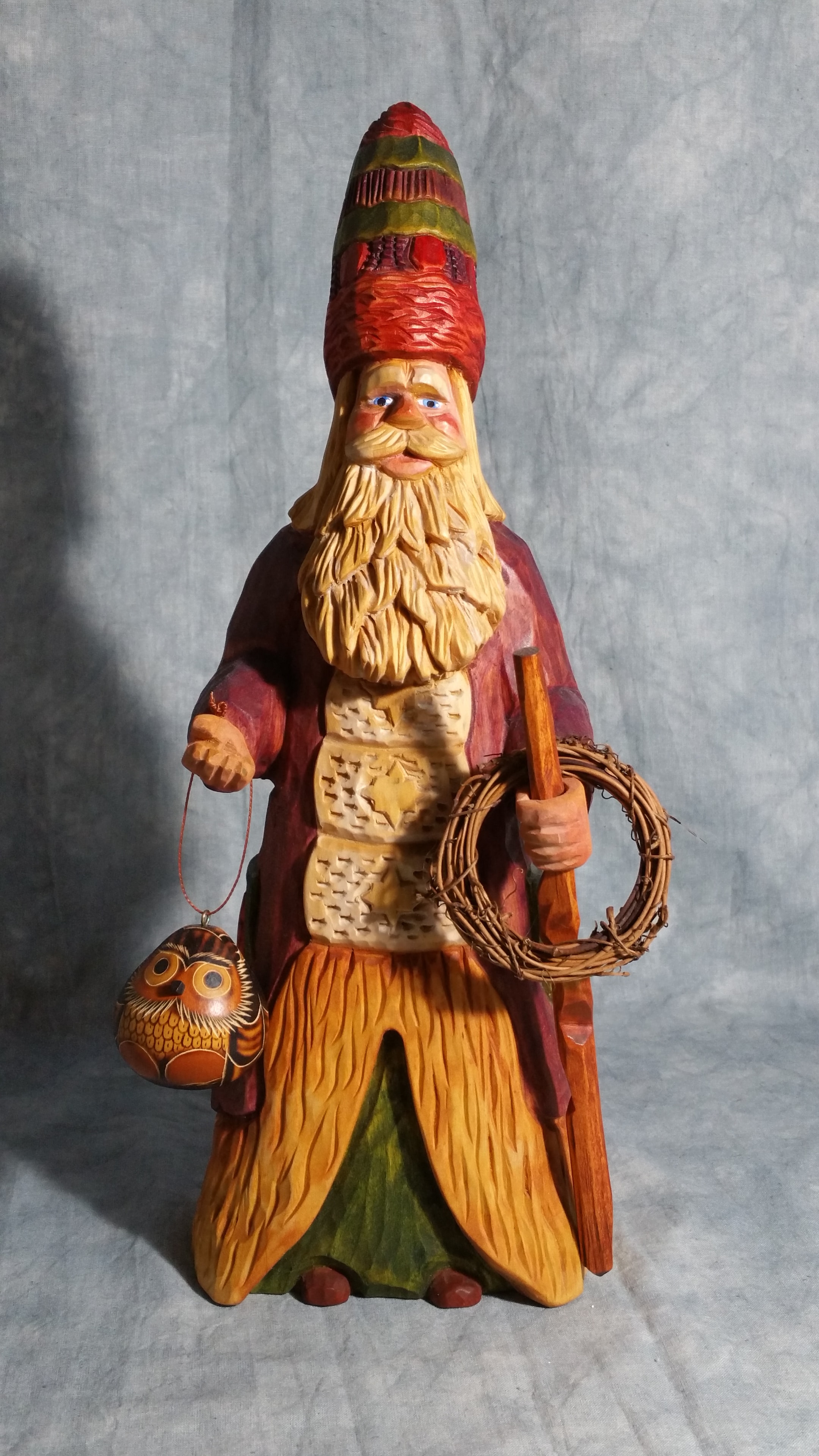 Large Father Christmas wood carving with angel, holly, and basket, shown beside a wine bottle for scale
