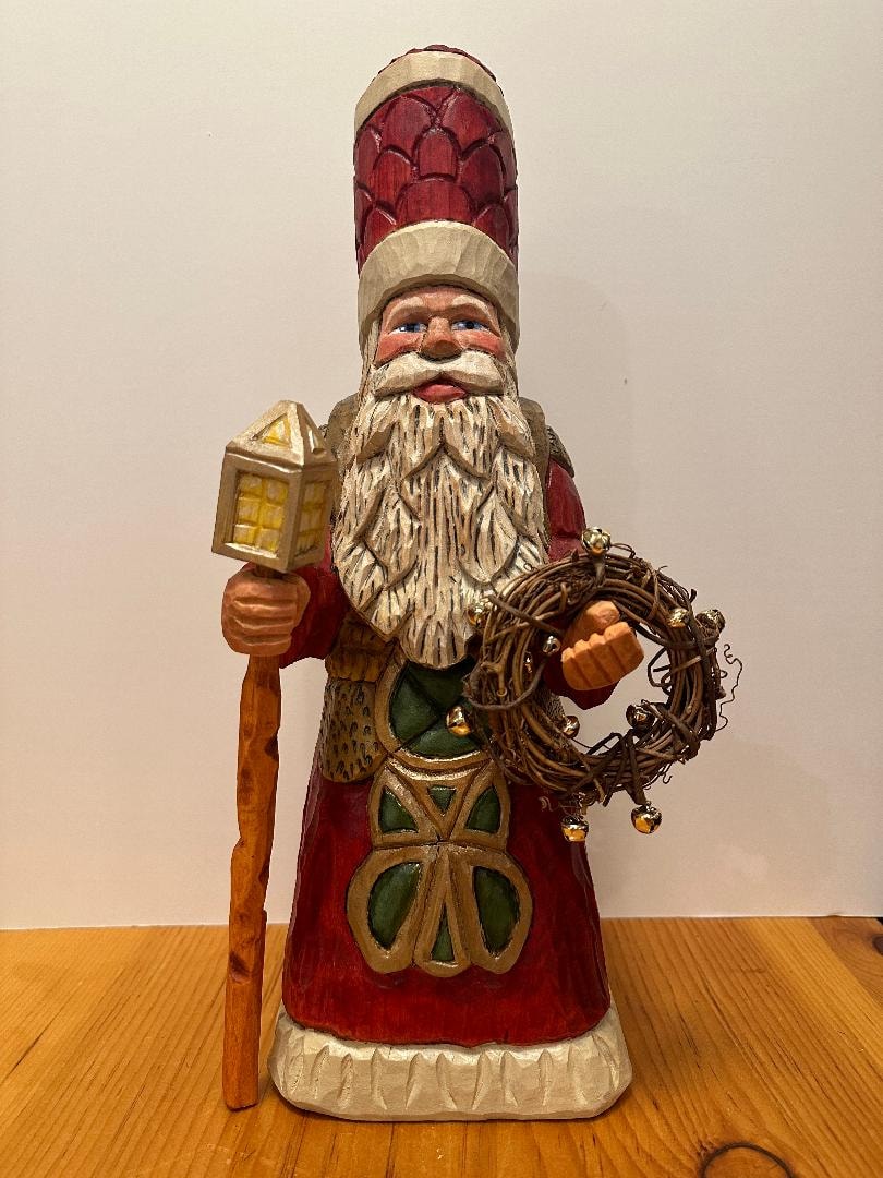 Father Christmas wood carving in red and green robe holding a wreath and owl ornament
